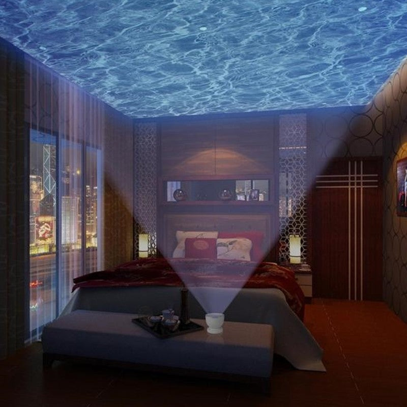 Room with a projected ocean ceiling and city lights visible through windows.