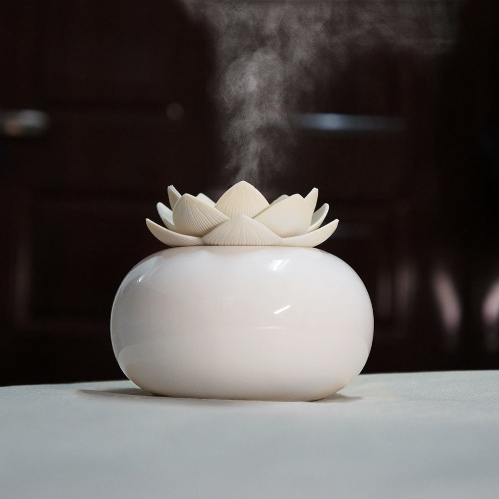 White ceramic diffuser with lotus design on a dark background