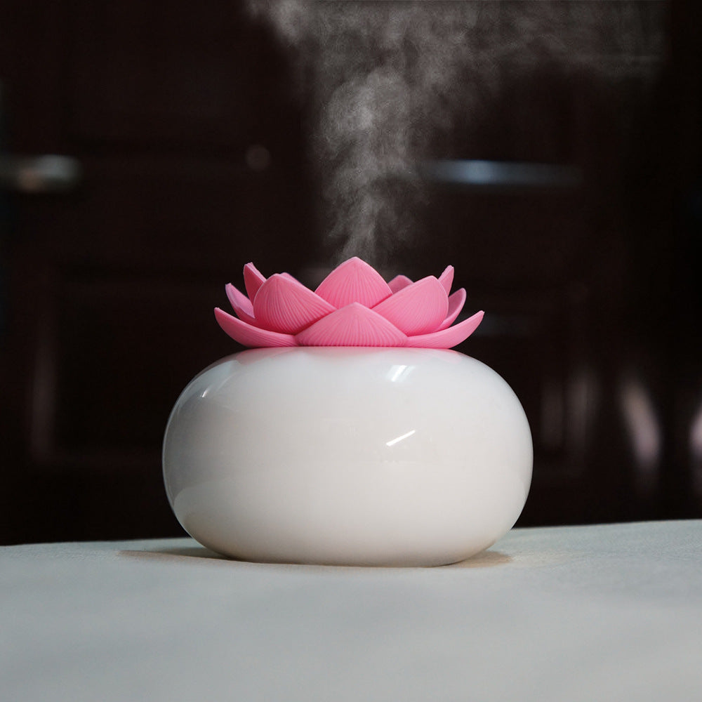 Pink lotus-shaped diffuser emitting steam on a dark background