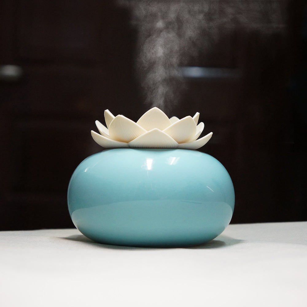 Ceramic diffuser with lotus design emitting steam on a dark background
