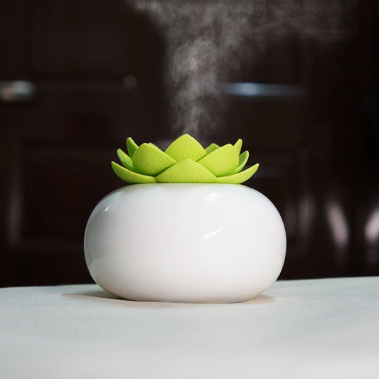 White humidifier with a green flower-shaped top on a dark background