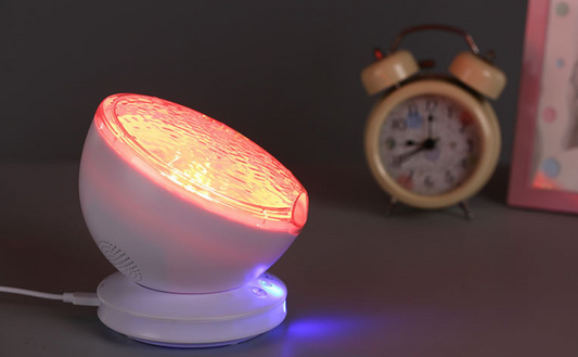 White night light emitting red and blue lights on a dark surface with a clock and photo frame in the background.