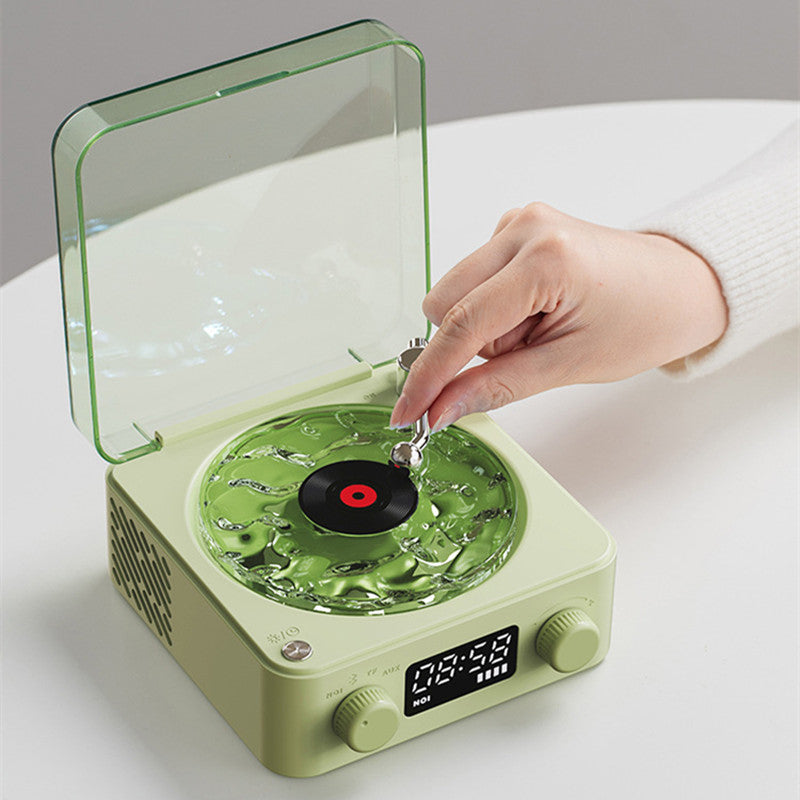 Green record player with a hand placing a red vinyl record on it, on a white surface.