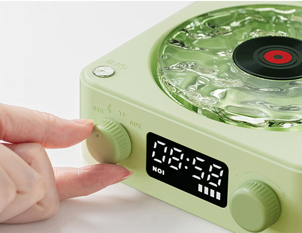 Green vintage-style radio with digital display and hand adjusting a knob on a white background